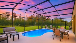 A covered outdoor swimming pool with a view of a grassy area and trees. - Amazing 8BR Family Villa at Veranda Palms ● Private Pool/BBQ/More! (Kissimmee)