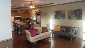 A spacious living room with a sofa and chairs, a dining area with a table and chairs, and a kitchen with wooden cabinets and appliances. - 2-Br Country Cottage on rolling hills of Burton, 15 min from Round Top! (Burton)