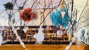Un aparador de madera con una guirnalda decorativa y varios adornos, incluyendo una figurita de pájaro blanco, un pájaro azul y una flor roja.