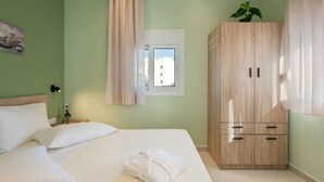 Une chambre à coucher comprenant un lit, une armoire, une fenêtre et une lampe fixée au mur.
