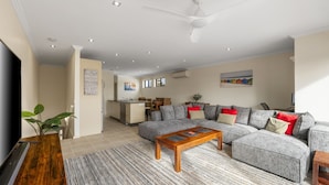 A spacious living room with a grey sectional sofa, a wooden coffee table, and a ceiling fan. - Brooklya by the Beach (Cowes)