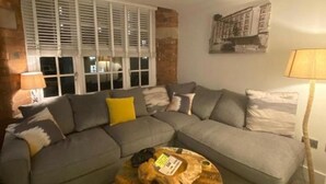 A living room with a grey sectional sofa, a round coffee table, and a lamp. - Cocoa Suites-2 Bed-city Centre-pets-parking (York)