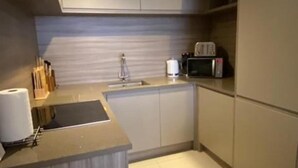 A compact kitchen with a sink, a microwave, and a toaster. There is a roll of paper towels and a knife block on the counter. - Cocoa Suites-2 Bed-city Centre-pets-parking (York)