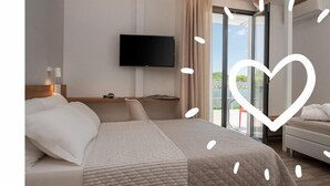 Ein Hotelzimmer mit einem großen Bett, einem flachbildfernseher an der Wand, einer Couch und einem Balkon mit Blick.