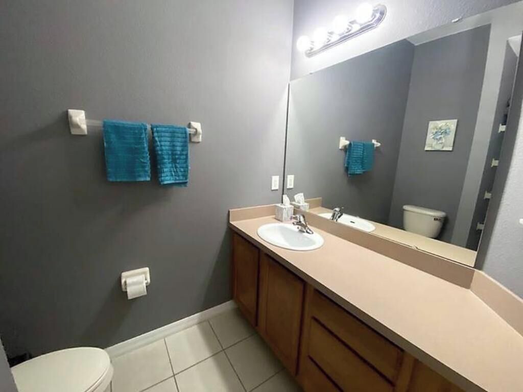 Un baño con un lavamanos blanco, un espejo y dos toallas azules colgadas en la pared.