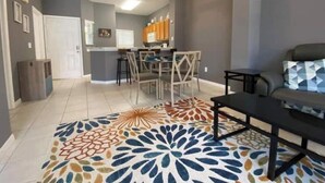 A modern living room with a dining area, grey walls, and a patterned rug. - Relaxing 3 Bedroom Townhome (Kissimmee)