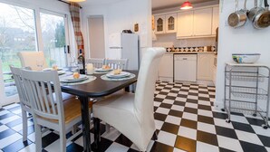A kitchen with a checkered floor, white cabinets, and a dining area with a table set for four. - Aughrim Holiday Village No 14 (Aughrim)