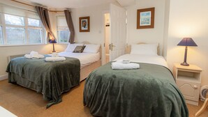 A hotel room with two beds, each with a green bedspread and white linens, a bedside table with a lamp, and a window with curtains. - Aughrim Holiday Village No 14 (Aughrim)