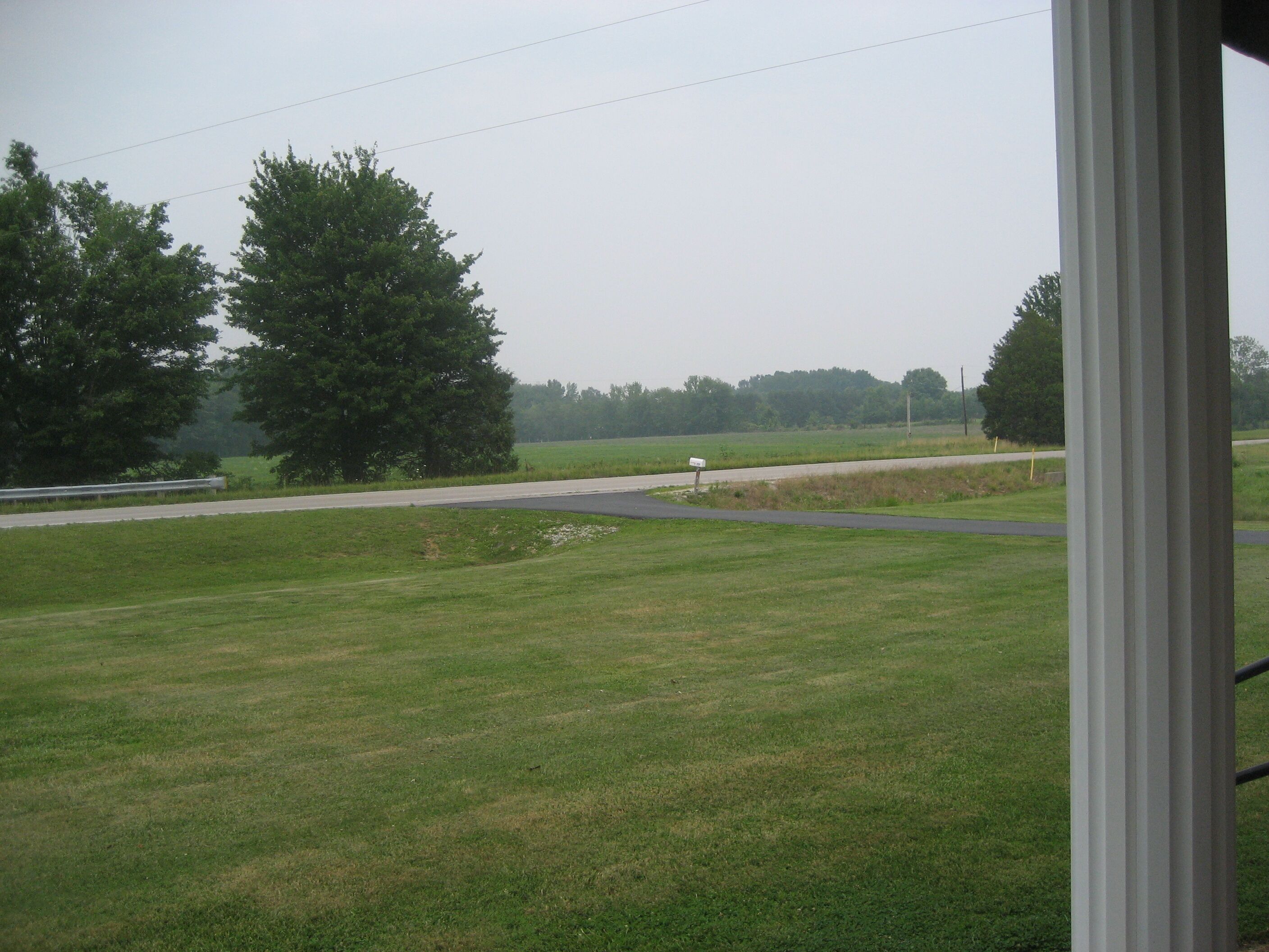 A grassy field with a road and a mailbox.