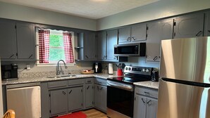 A modern kitchen with grey cabinets, stainless steel appliances, and a red rug on the floor.