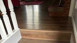 Een houten trap met witte zuiltjes en een rood tapijt op de achtergrond.