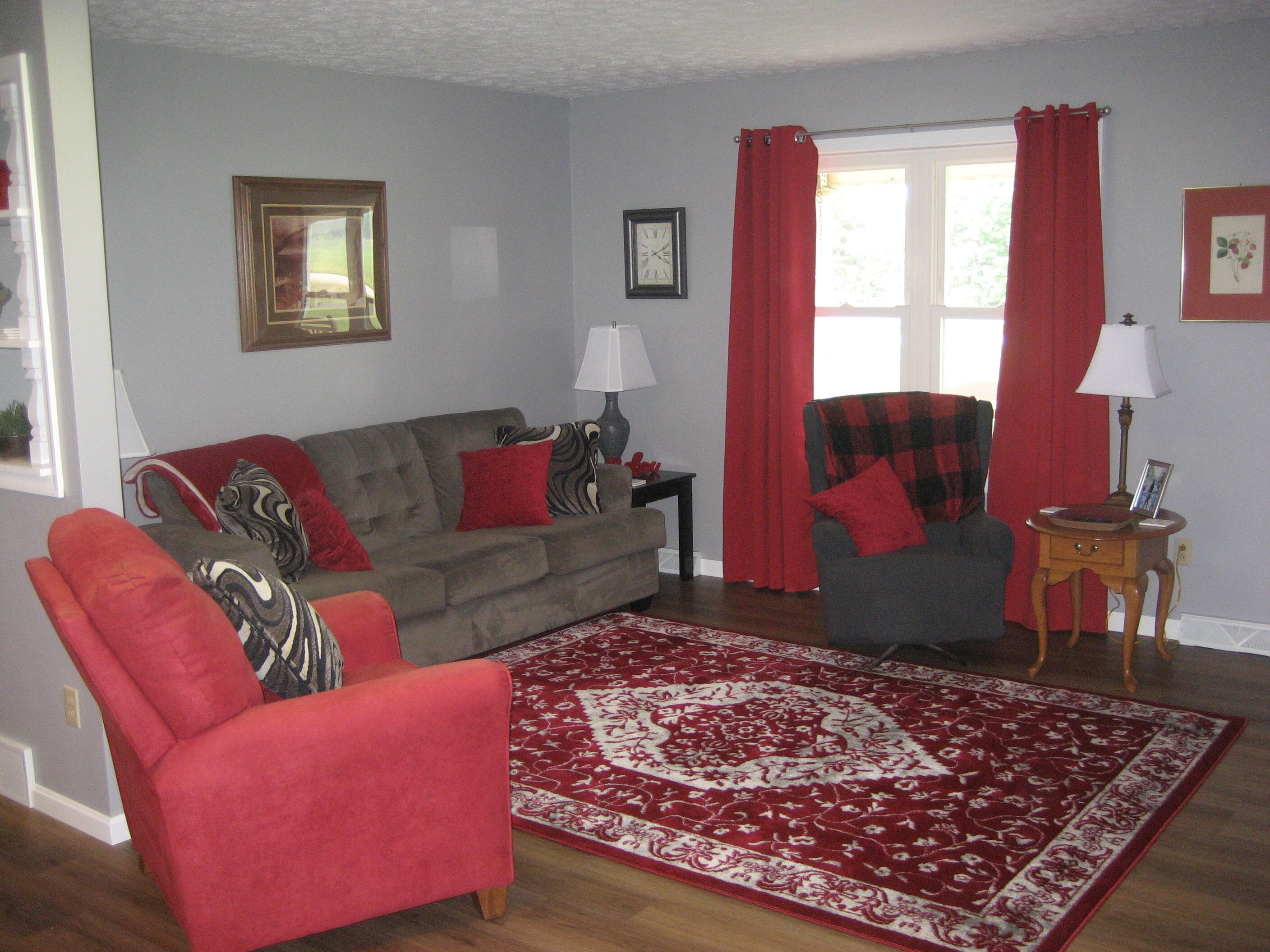 A living room with a grey sofa, red armchair, and patterned rug.