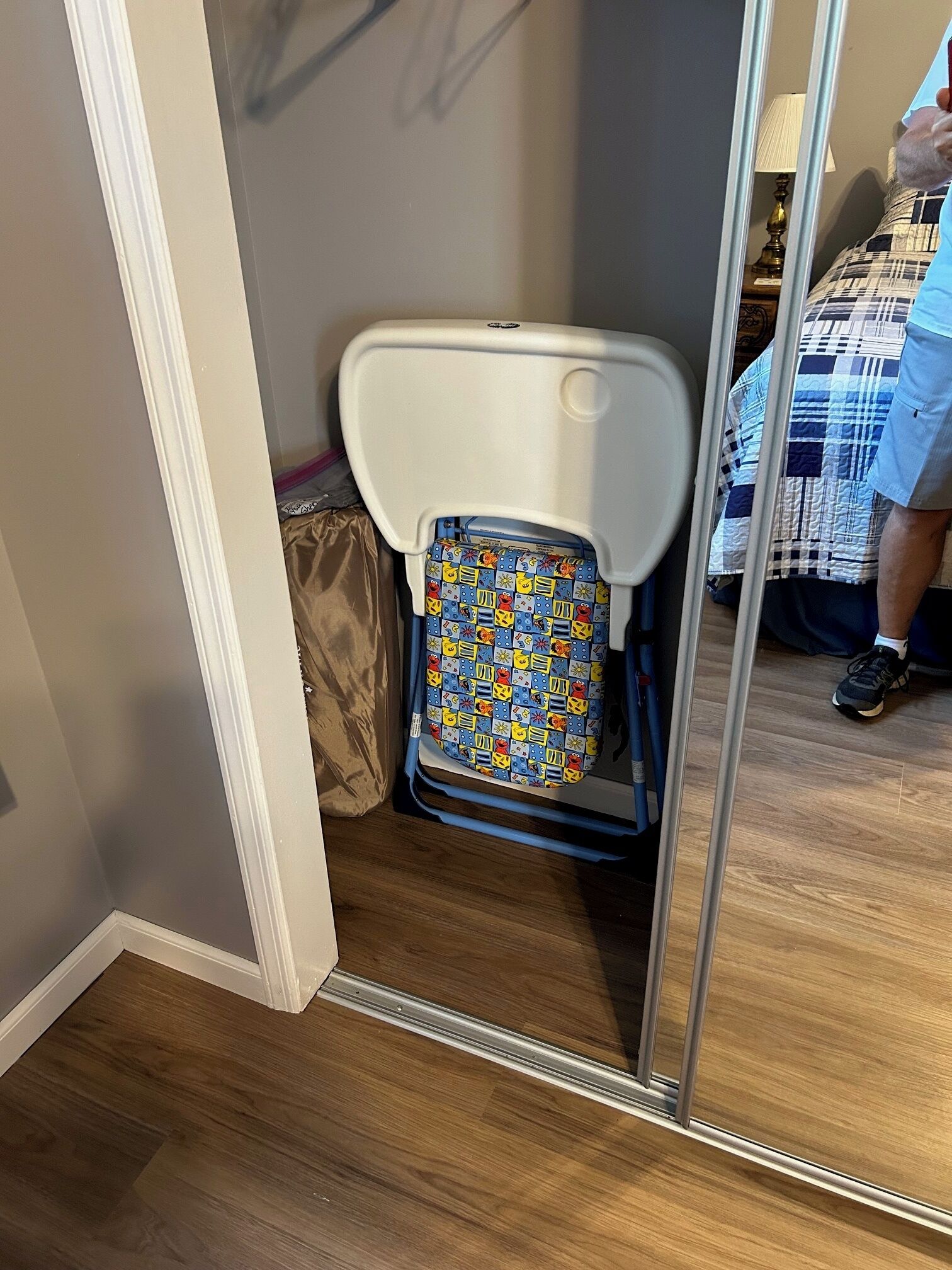 Un baño pequeño con inodoro blanco, una cubierta de asiento estampada en azul y amarillo, y piso de madera.