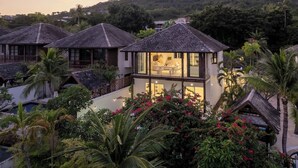 Un resort con varias edificaciones tipo bungalow, una piscina y exuberante vegetación tropical.