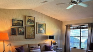 A cozy living room with a sofa, a coffee table, a lamp, and a ceiling fan. - Perfect Poolhouse (Linden)