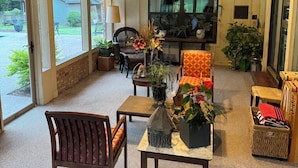 A cozy living room with a fireplace, comfortable seating, and a view of the outdoors. - Perfect Poolhouse (Linden)