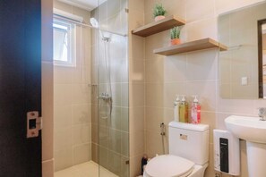 Bathroom features a glass-enclosed shower, toilet, and sink with a mirror.