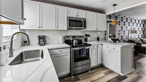 Una cocina moderna con armarios blancos, electrodomésticos de acero inoxidable y suelo de madera.