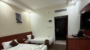 Ein Hotelzimmer mit zwei Betten, einem Schreibtisch, einem Fernseher und einer Tür.