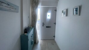 Ein Flur mit einer zur Kammer führenden Tür, einem kleinen Fenster und einem an der Wand befestigten Bilderrahmen.