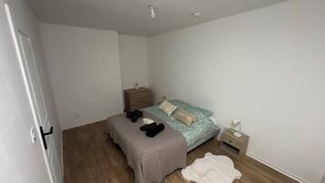 Une chambre à coucher comprenant un lit, une table de chevet, une commode, une porte et un luminaire.