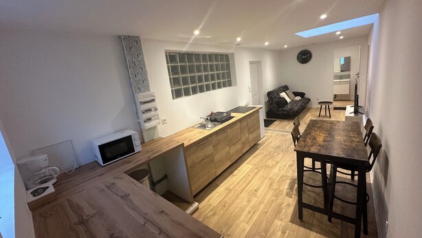 A modern kitchen with wooden countertops, a built-in oven, and a dining area with a wooden table and chairs. - 2chambres • 6 people - Near beach / cap blanc nez (Calais)