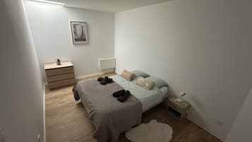 Un dormitorio con cama, mesita de noche, cómoda, radiador y un cuadro en la pared.