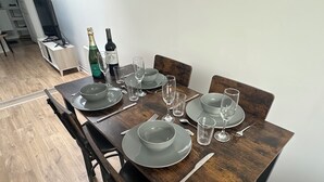 A dining table set with plates, glasses, cutlery, and bottles, in a room with wooden flooring and chairs. - 2chambres • 6 people - Near beach / cap blanc nez (Calais)