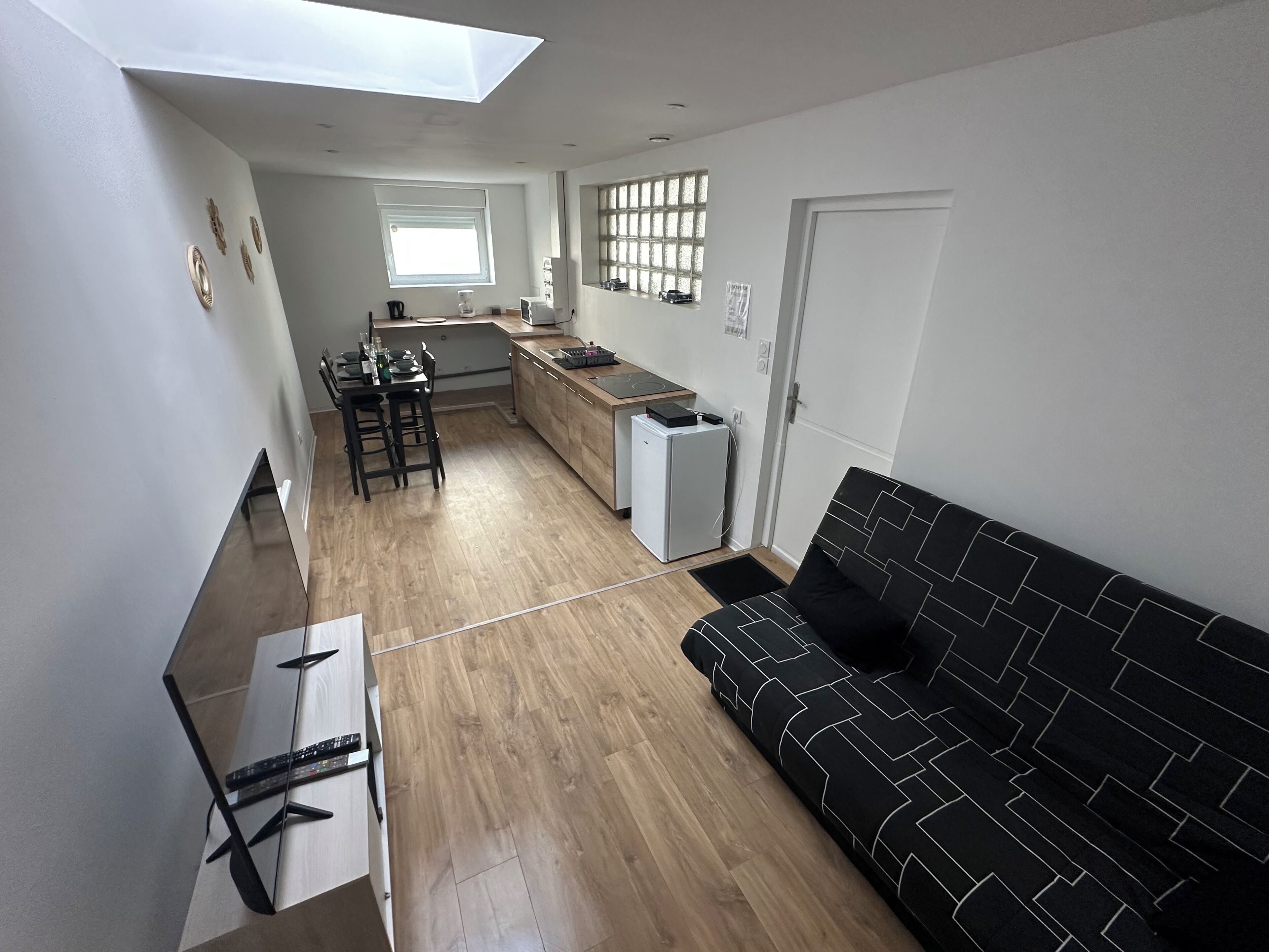 Un espacio habitable moderno con sofá, mesa de comedor y zona de cocina.