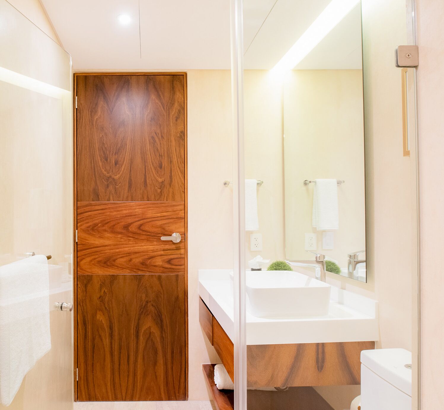 A modern bathroom with a wooden vanity, a white sink, and a toilet.