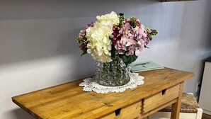 Un escritorio de madera con un florero y una libreta.