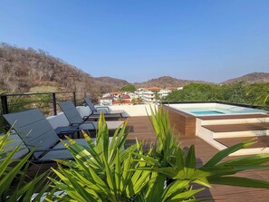 A poolside area with lounge chairs and a hot tub.