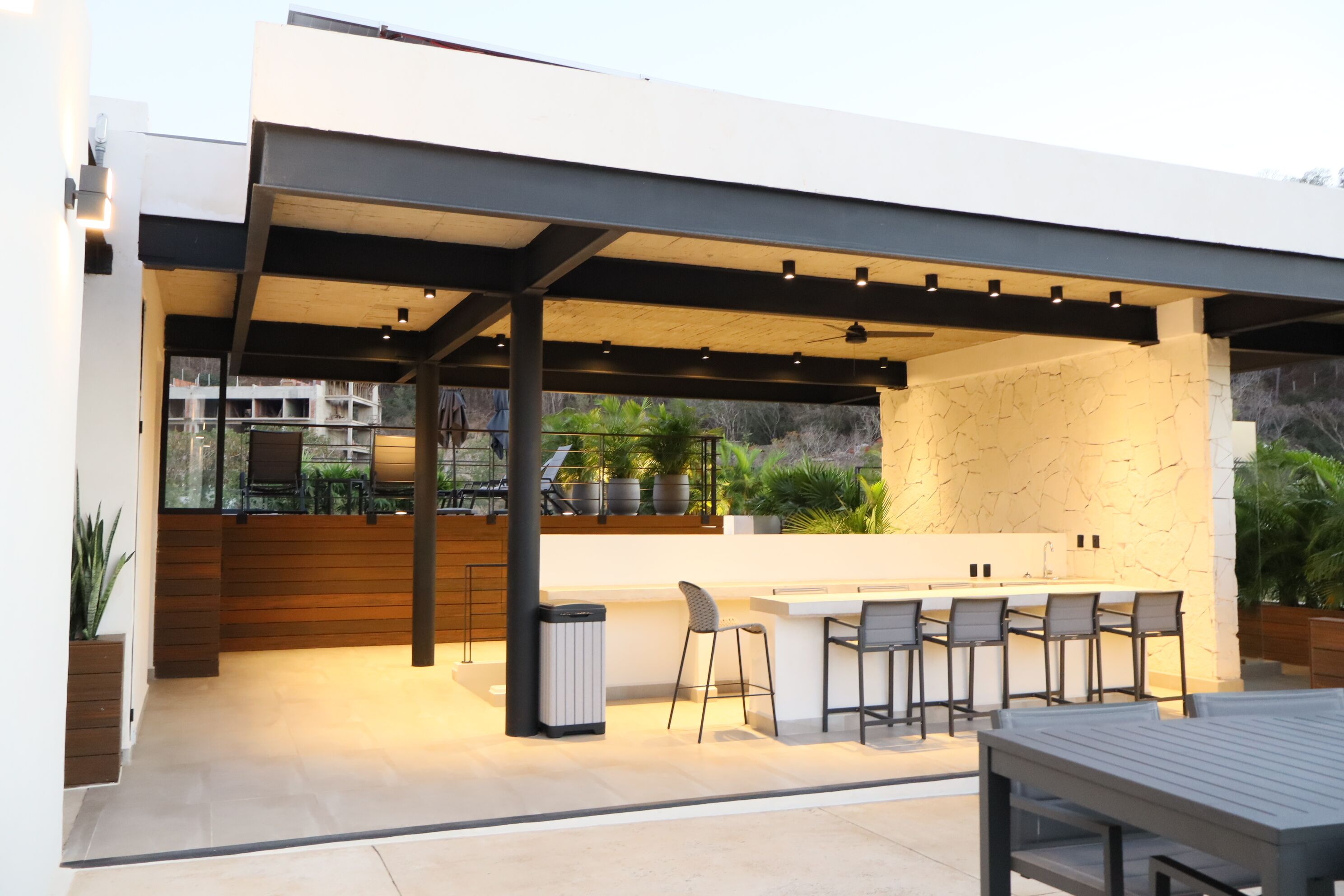 An outdoor patio with a bar area, seating, and a view of the surrounding landscape.