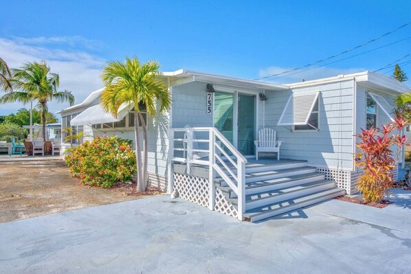 A single-story mobile home with a covered porch, a small set of steps leading to the entrance, and a number '75' on the door. - On Island Time! HotTub-Water View (Marathon)