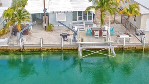A waterfront property with a dock, outdoor seating, and palm trees. - On Island Time! HotTub-Water View (Marathon)