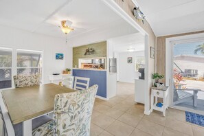 A spacious living area with a dining table, chairs, a kitchen island, and a balcony with a railing. - On Island Time! HotTub-Water View (Marathon)