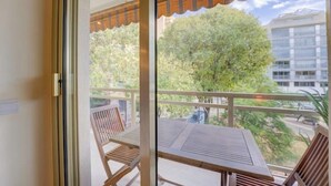 A balcony with a table and chairs, a view of trees and buildings, and a patterned awning. - Elegant Apt w/2 Terraces/Mins to Beach & Shops (Antibes)