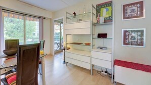 A modern room with a dining area, a glass-fronted shelving unit, and a red bench. - Elegant Apt w/2 Terraces/Mins to Beach & Shops (Antibes)