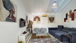 A living room with a sofa, a coffee table, a TV, and artwork on the walls. - Barra do Sahy 1 (Sao Sebastiao)