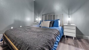 Une chambre à coucher avec un lit, deux tables de chevet et une petite table d’appoint.