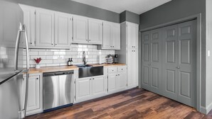 Une cuisine moderne avec des meubles blancs, des appareils en acier inoxydable et un plan de travail en bois.