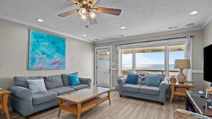 A spacious living room with two grey sofas, a wooden coffee table, and a ceiling fan. - Just For The Halibut 
Ocean Front Stay
Pet-Friendly (Emerald Isle)