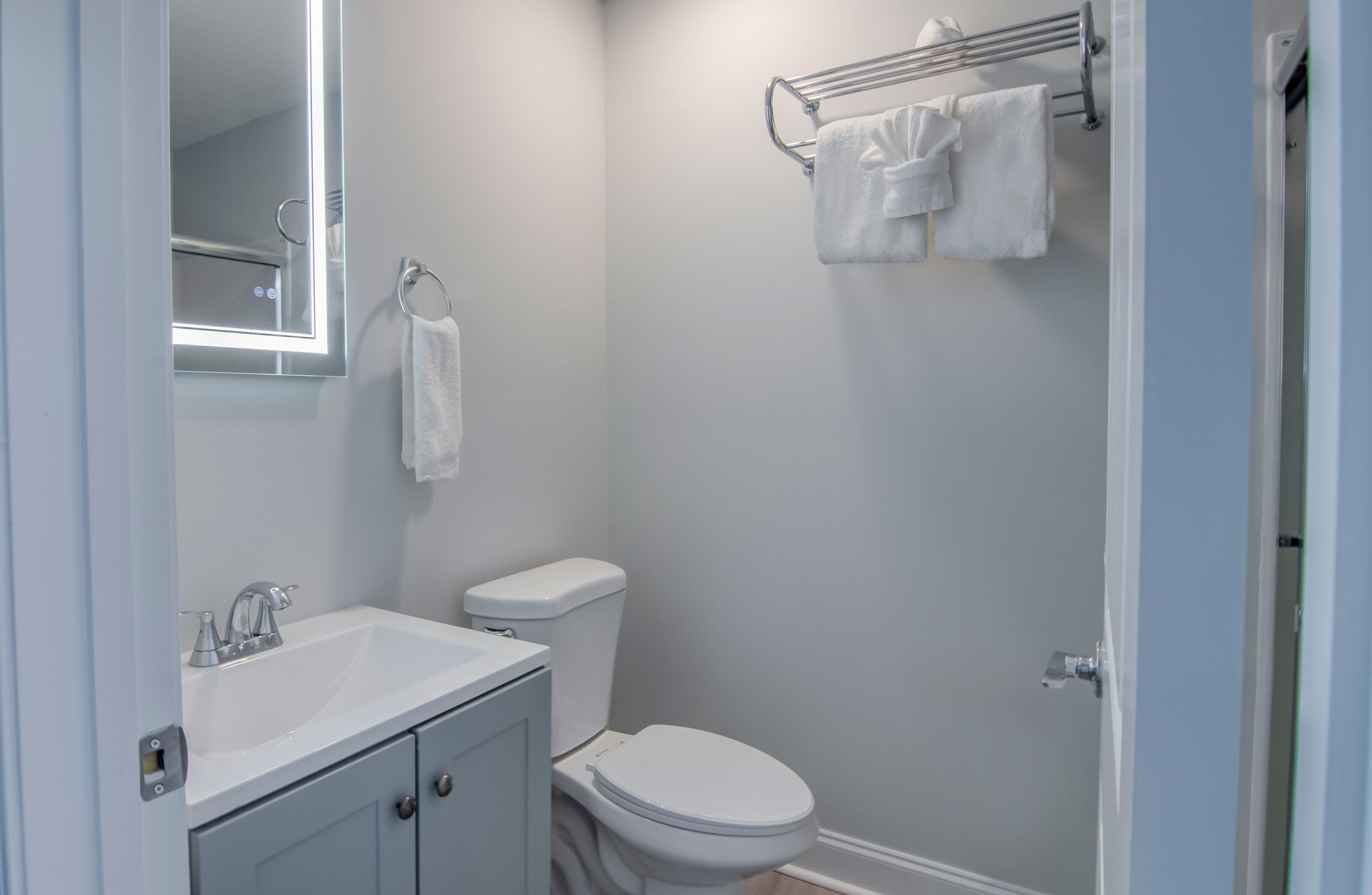 A bathroom with a white sink, toilet, and towel rack.