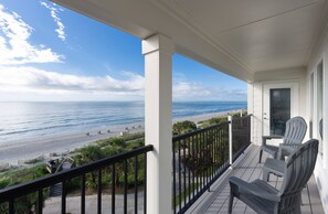 A balcony with a view of the beach and ocean.