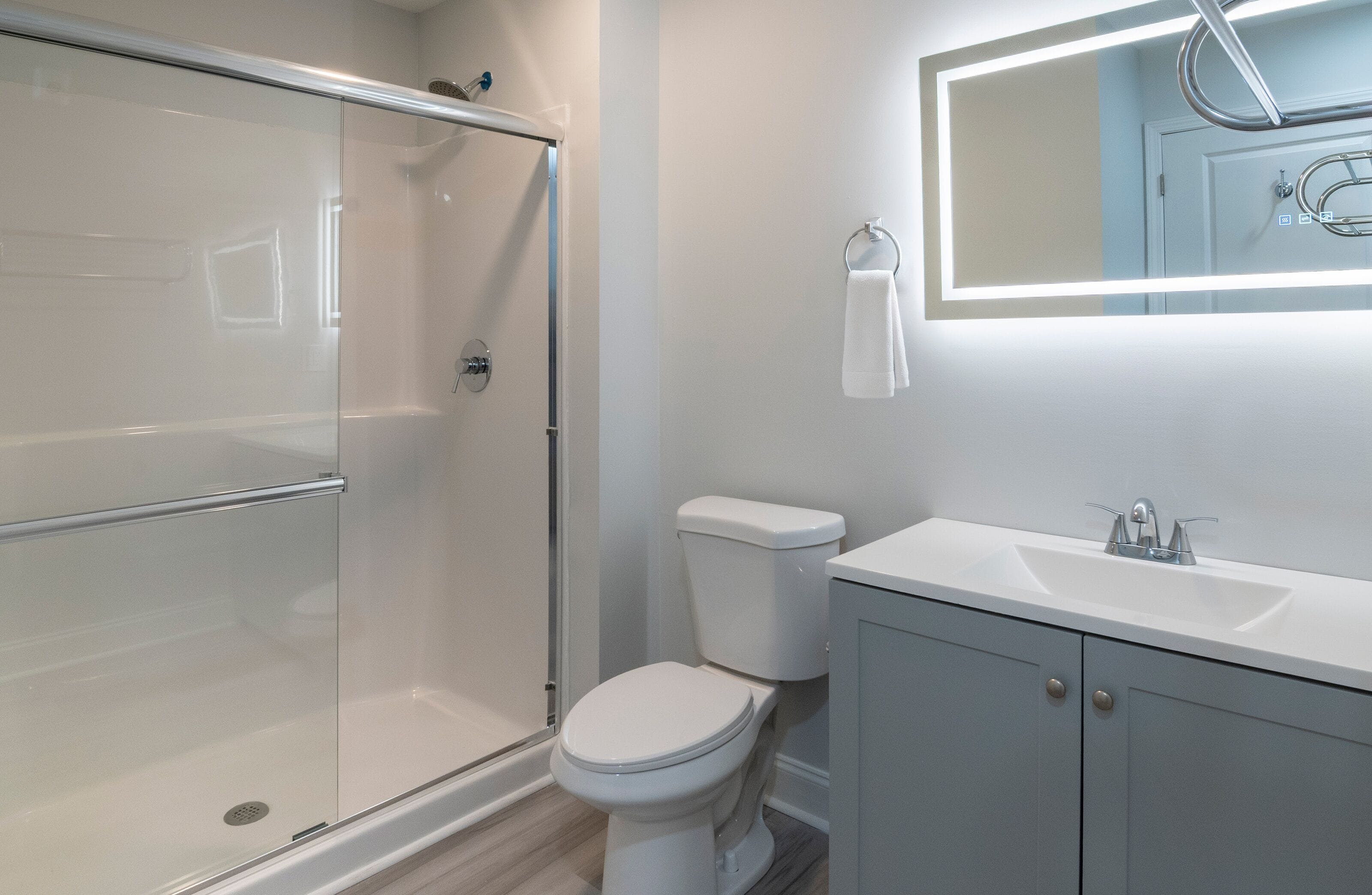 A modern bathroom with a glass-enclosed shower, a white toilet, and a vanity with a mirror.