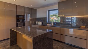 Una cocina moderna con encimeras de granito, electrodomésticos de acero inoxidable y un amplio ventanal con vistas a la ciudad.