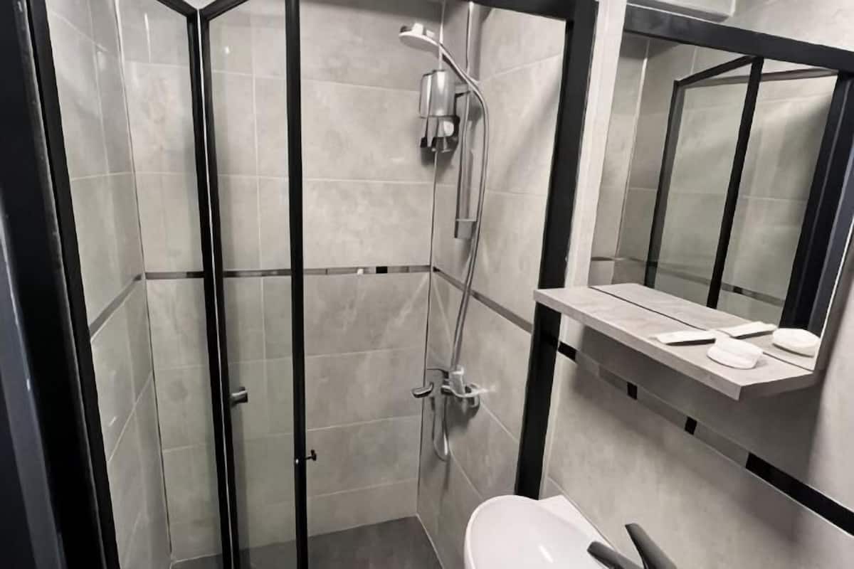 A modern bathroom with a glass-enclosed shower, a white sink, and a mirror above the countertop.