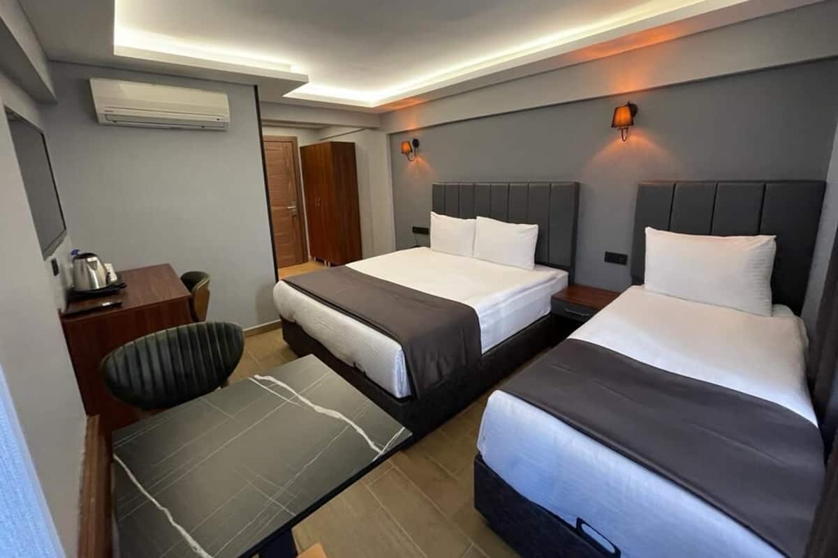 A hotel room with two beds, a desk, a chair, and a small table.