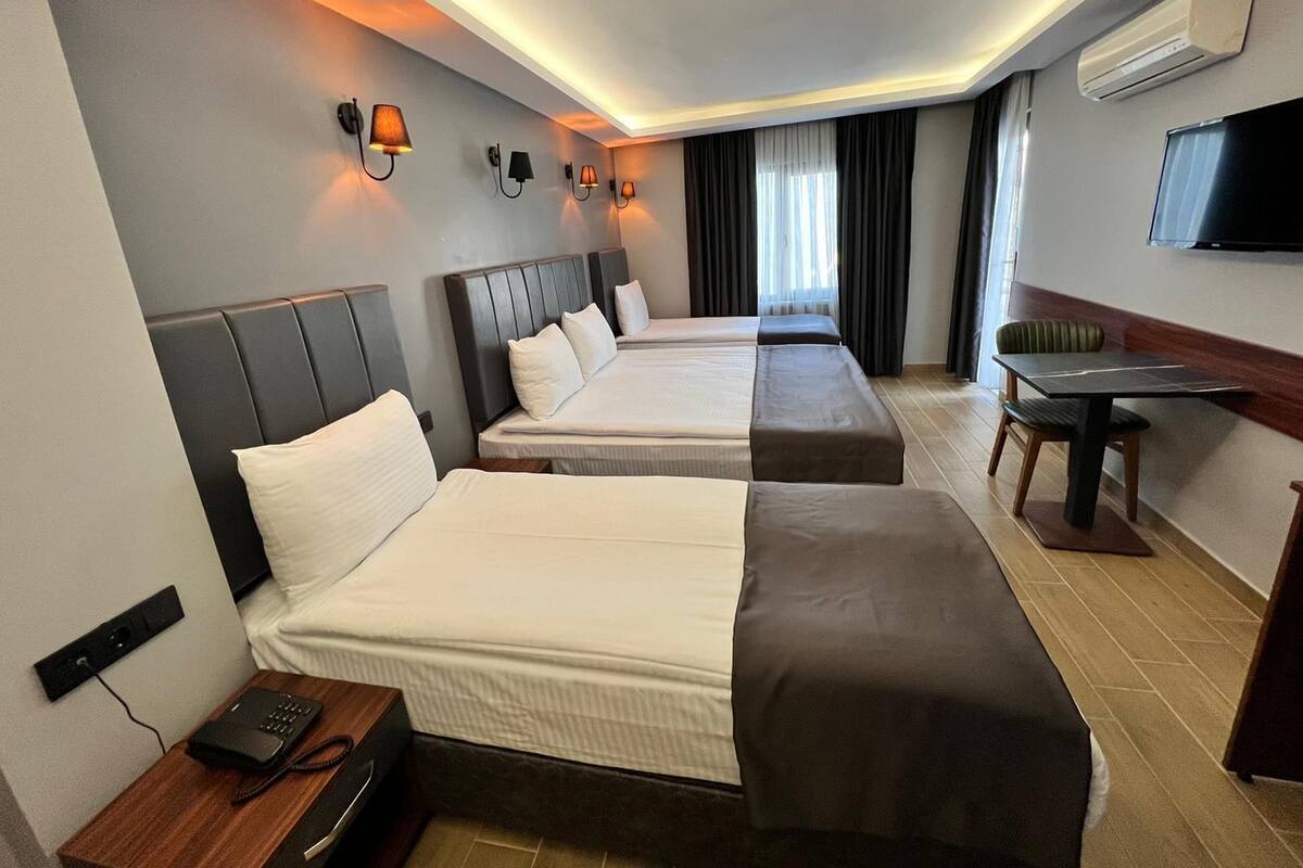 A hotel room with two beds, a desk, a chair, and a TV.