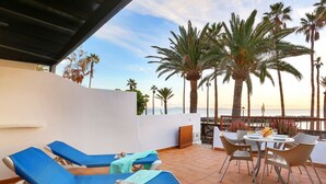A terrace with sun loungers and a table with chairs, overlooking palm trees and the sea. - Playa Flamingo  Margarita (Playa Blanca)